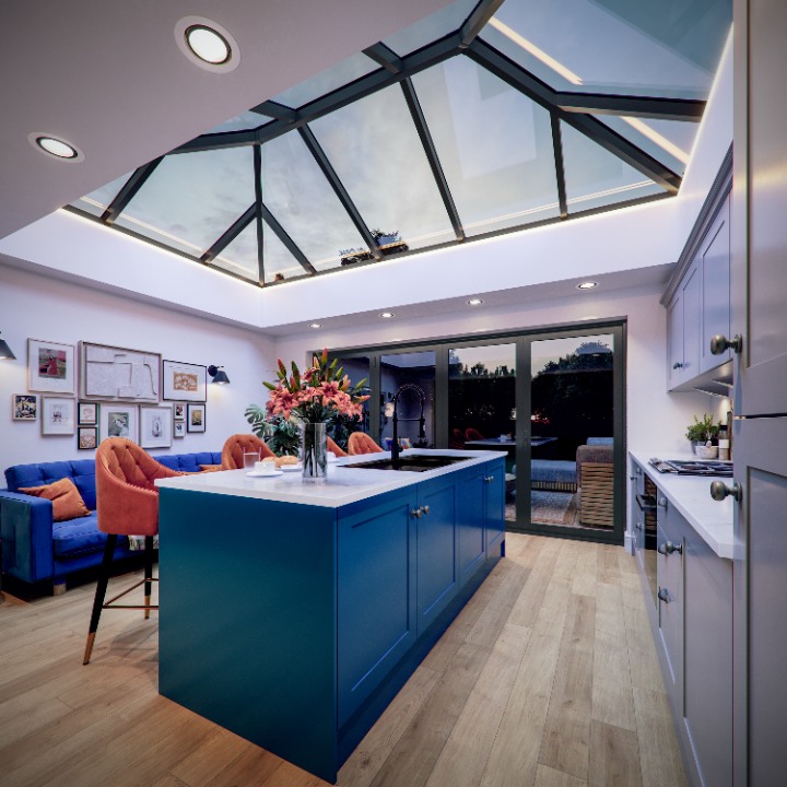 An interior view of a modern kitchen extension at dusk, looking up at a large Iconiq lantern roof illuminated by integrated perimeter LED lighting.