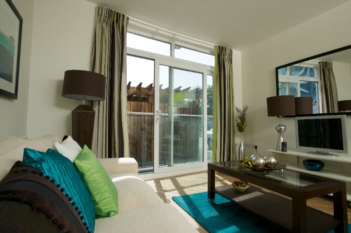 White Syncro sliding patio doors in a bright, modern living room with teal and green accents.